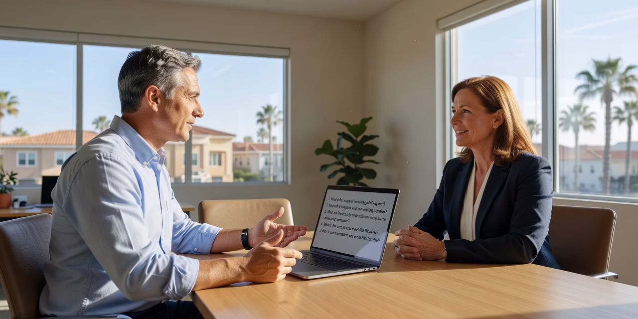 An internal IT staff member and an outside IT technician reviewing a support ticket dashboard together
